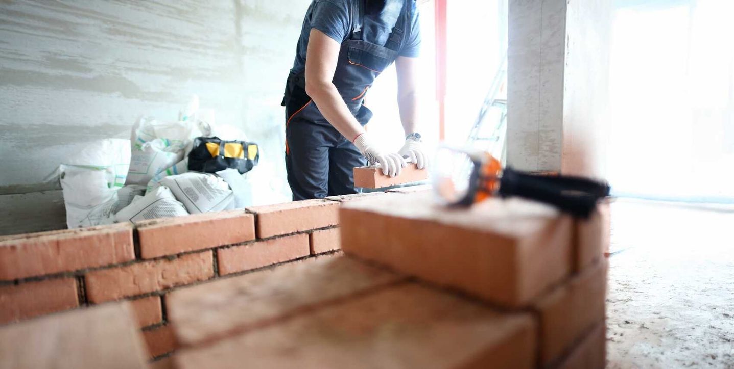 Ein Handwerker verputzt eine Ziegelwand